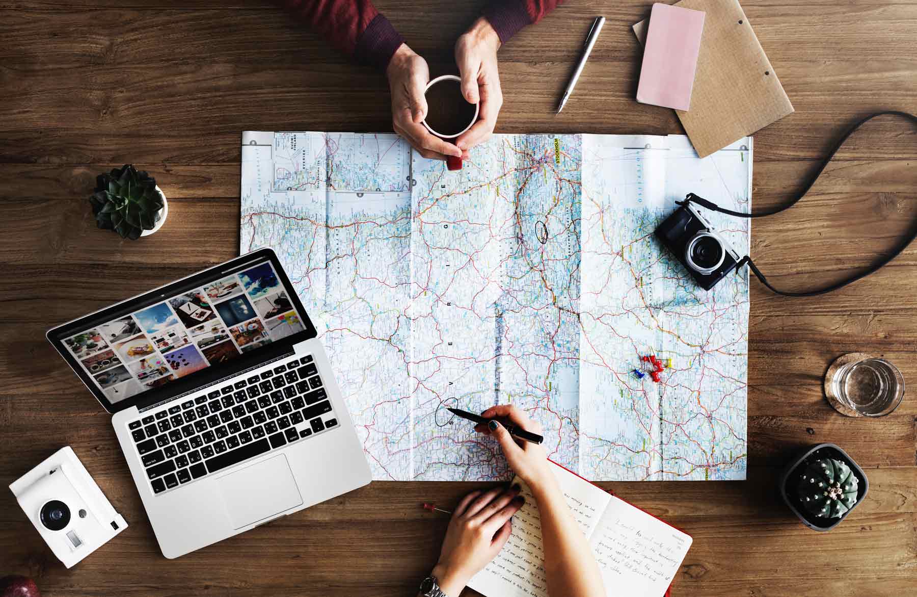 Travel supplies and map laid out on table, writing a to do list.