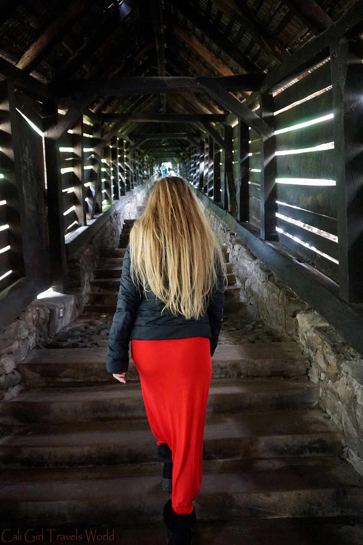 Female blonde traveler walking up a staircase through a tunnel in Sighisoara, Translyvania, Romania.