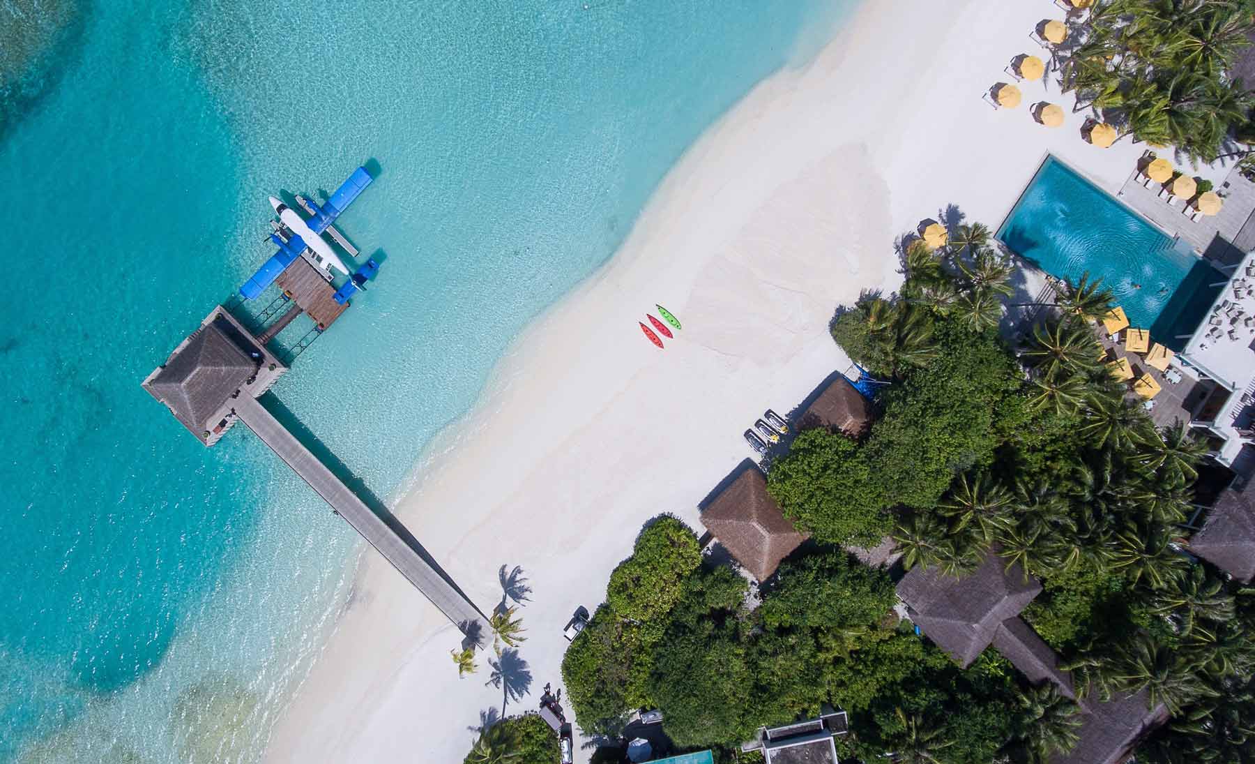 Small water plane on an island with white sand and bright blue clear waters.